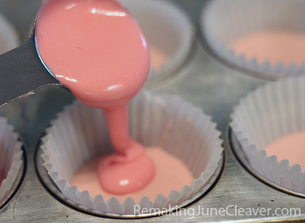 Layering pink cupcake batter into paper liners