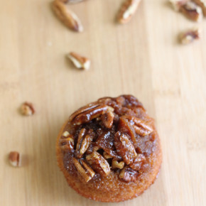 a Pecan Cornmeal Muffin with pecans laying around it on a wooden block