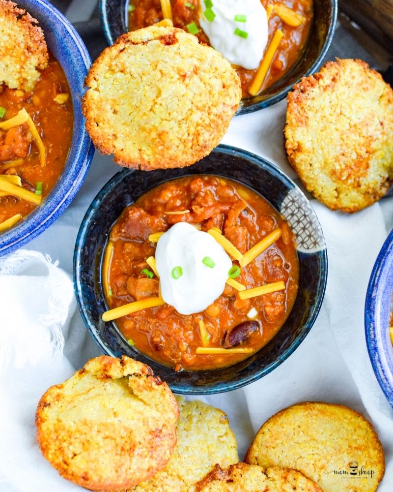 Muffins made from cornmeal next to a bowl of chili
