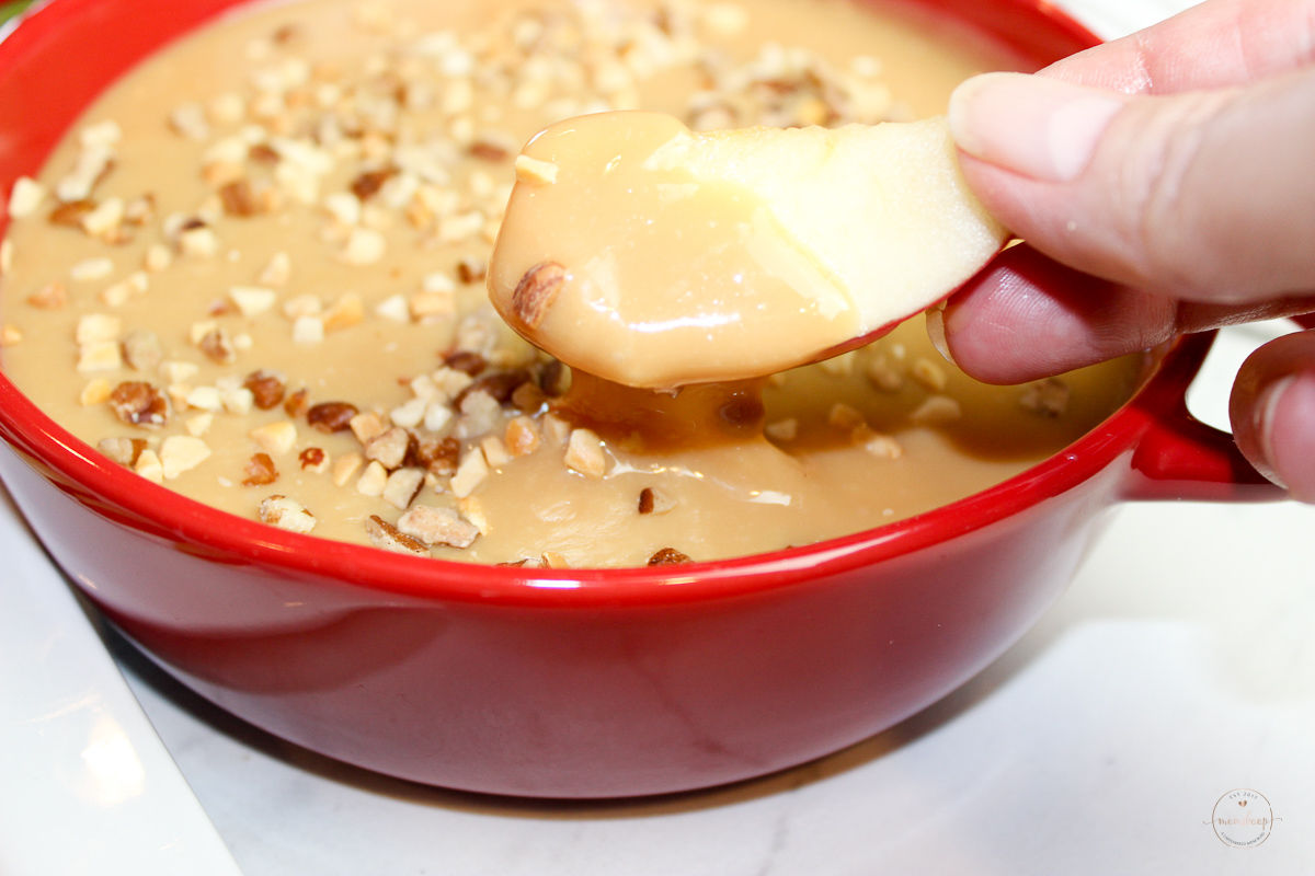 An apple slice dipped in caramel dip