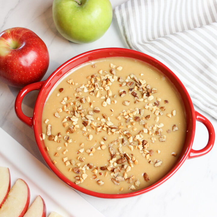 Apple slices with creamy caramel dip in a red bowl