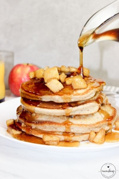 Stack of pancakes with apple topping and maple syrup