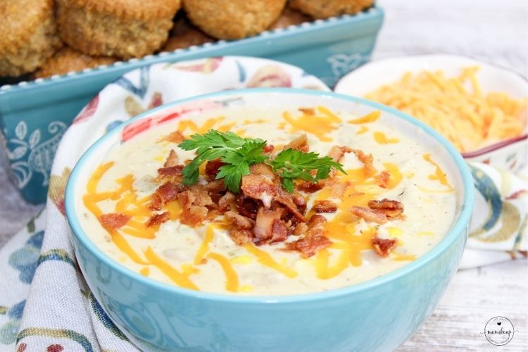 Crack White Chicken Chili in a blue bowl with bacon and cheese with cornbread muffins