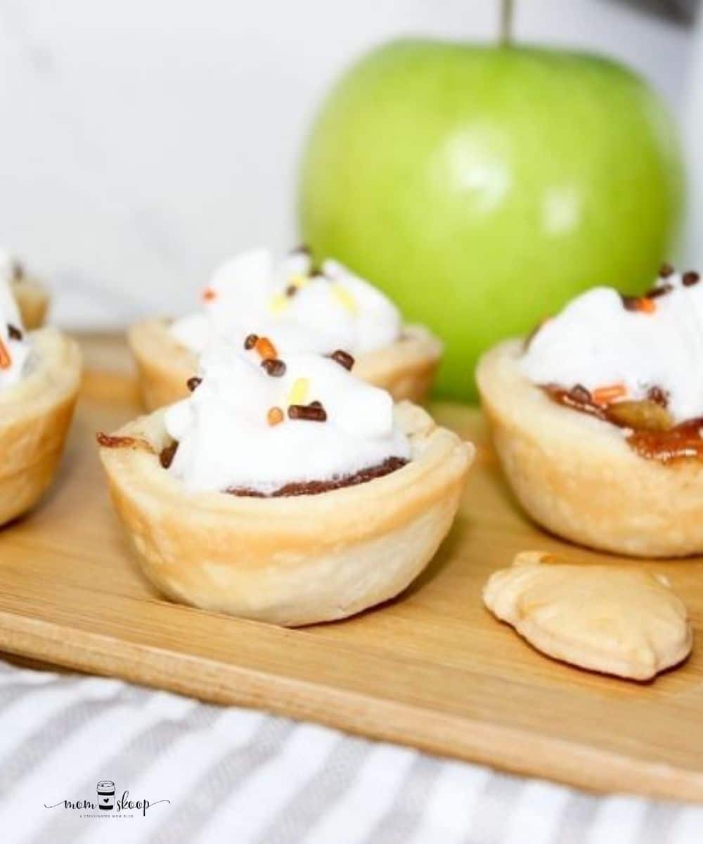 Mini Apple Pie Bites on a wooden tray with a green apple behind them