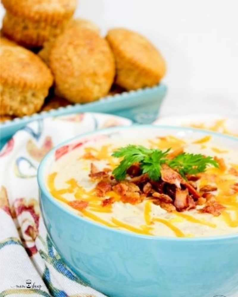 Blue bowl full of white chicken chili topped with bacon and cheese.