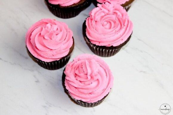 Strawberry infused pink frosting on top of chocolate cupcakes