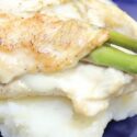 Stuffed Chicken Breast with cheese and asparagus placed on top of mashed potatoes