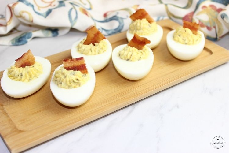 Thanksgiving Deviled Eggs topped with bacon on a bamboo tray
