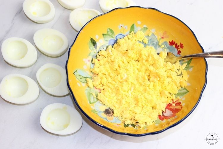 Smashing egg yolks with a fork.