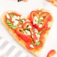 Heart Shaped Personal Pan Pizzas on a white countertop and next to a gray striped napkin