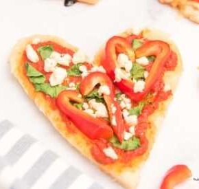 Heart Shaped Personal Pan Pizzas on a white countertop and next to a gray striped napkin