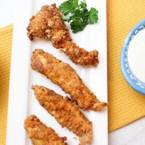 Chicken tenders made at home on a white serving tray with ranch dip