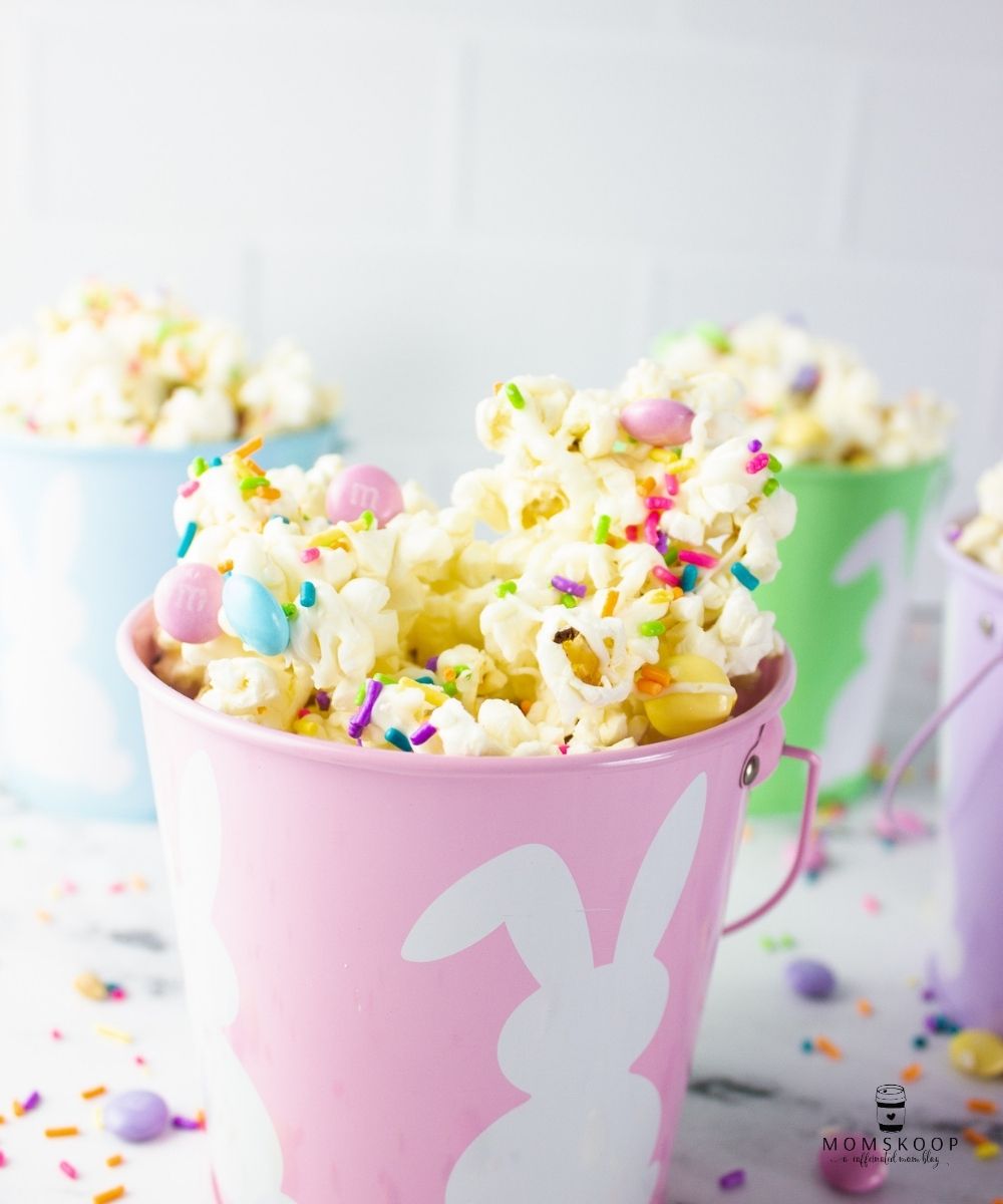 Pink, green, purple, and blue buckets with bunnies full of Easter Popcorn