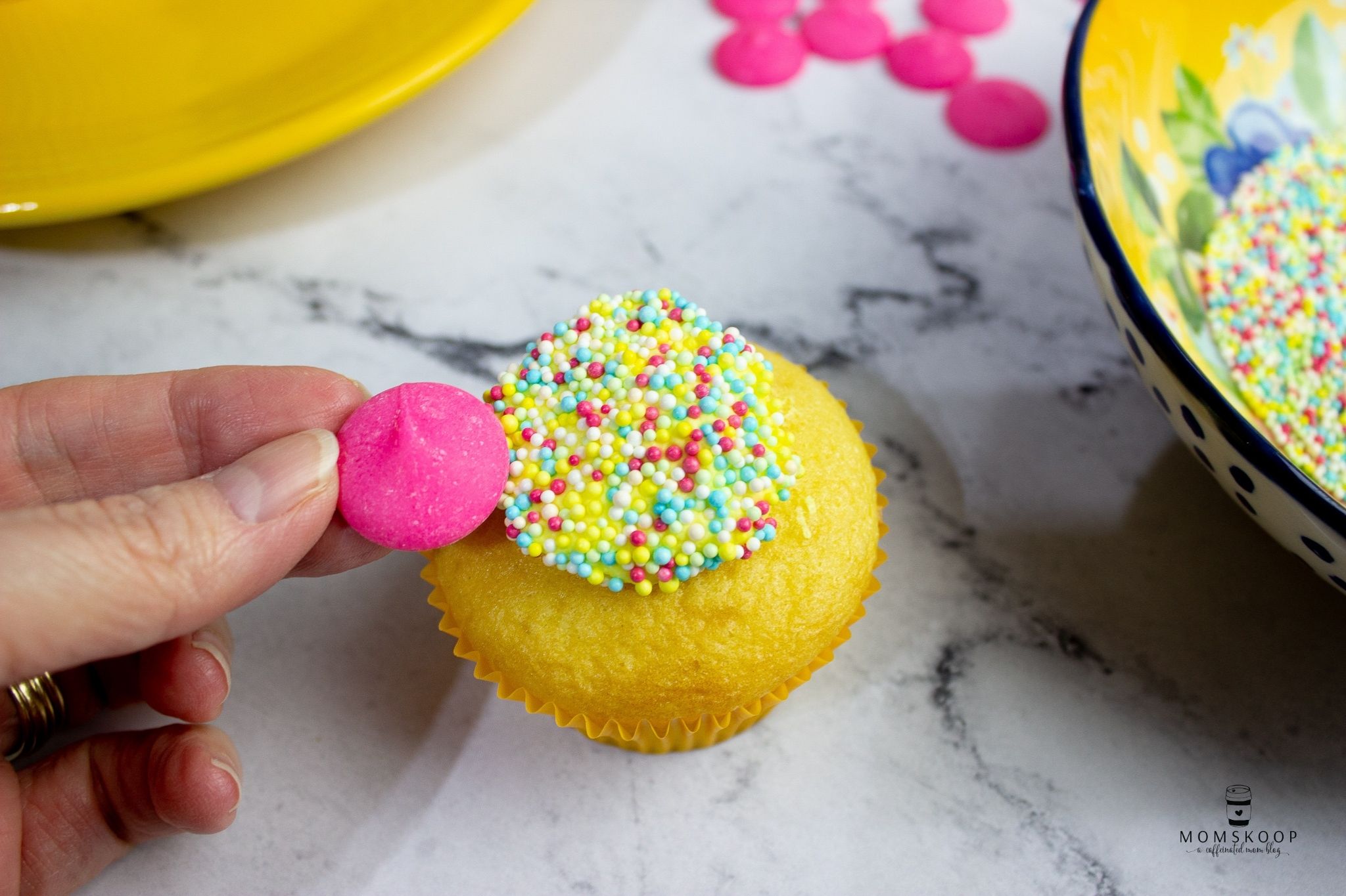 Adding a pink wafer onto the cupcake to make the daisy petals