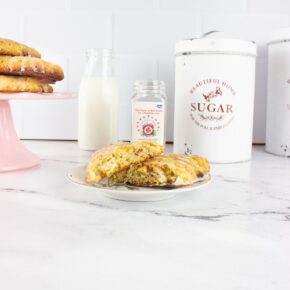 A White Chocolate Cranberry Scone on a white china plate with milk, pink cake stand with scones