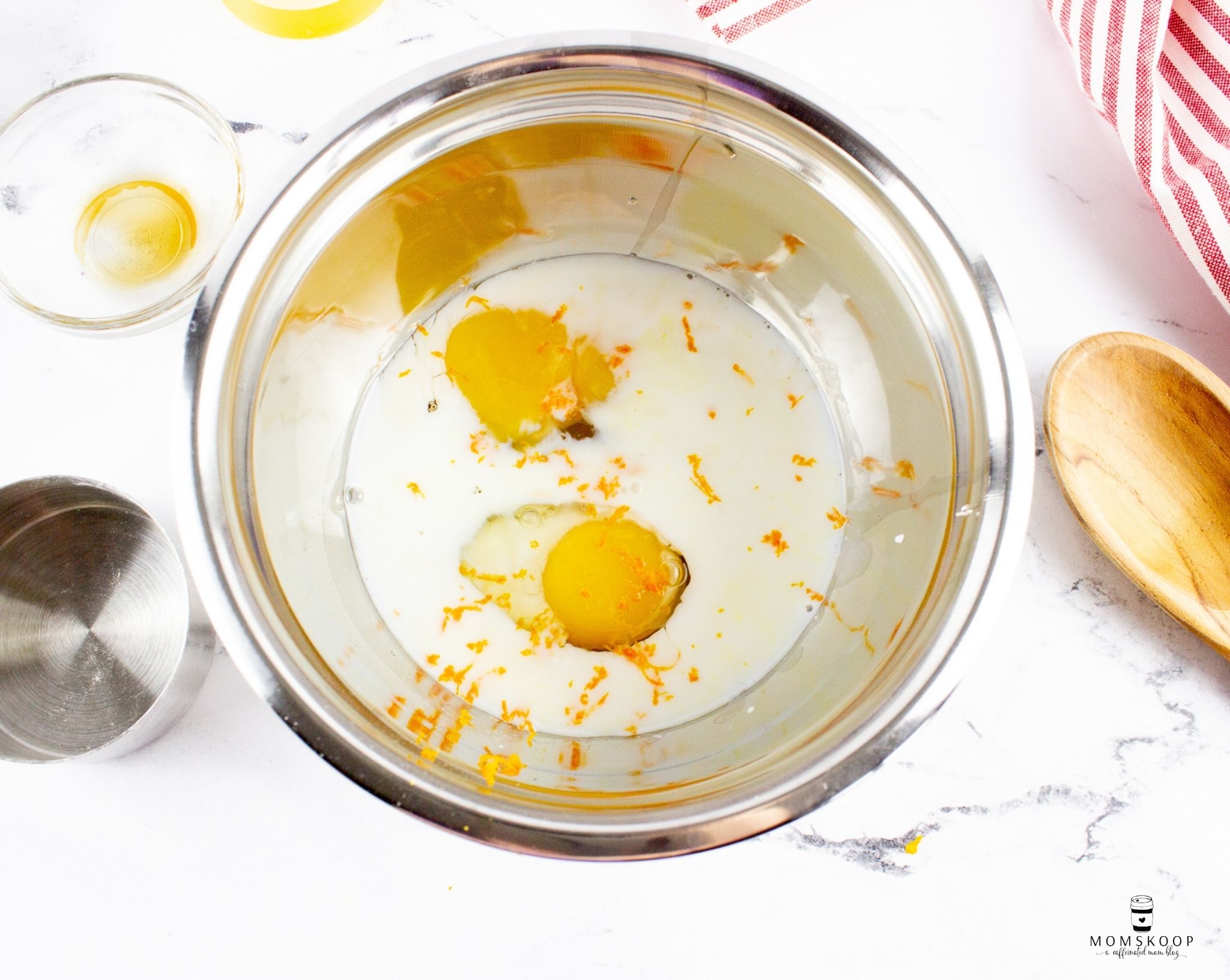 Milk, eggs, and orange zest in a stainless steel bowl
