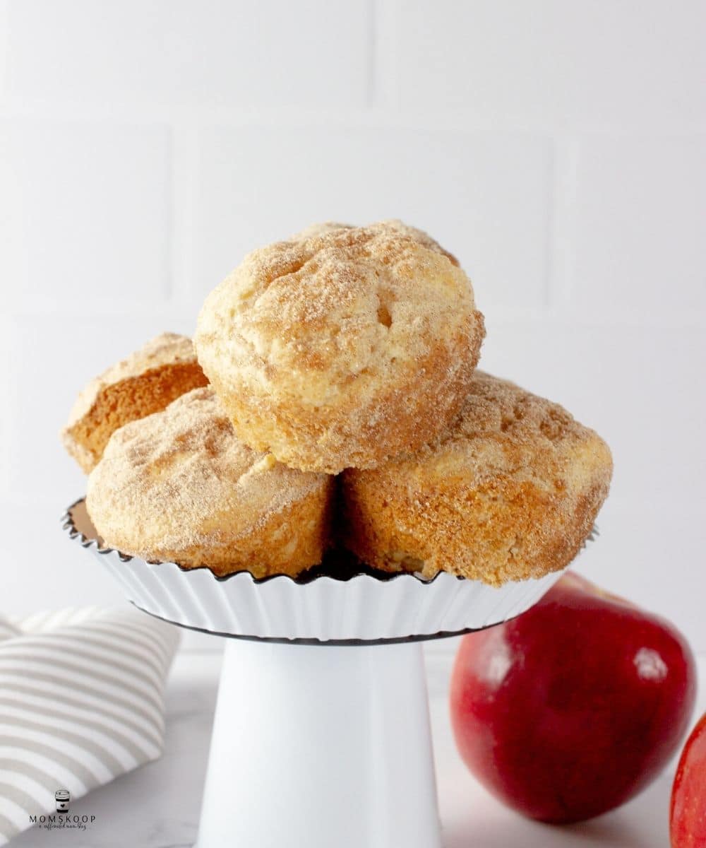 Cinnamon Muffin Melts stacked on a mini white cake stand with two red apples and a gray striped napkin