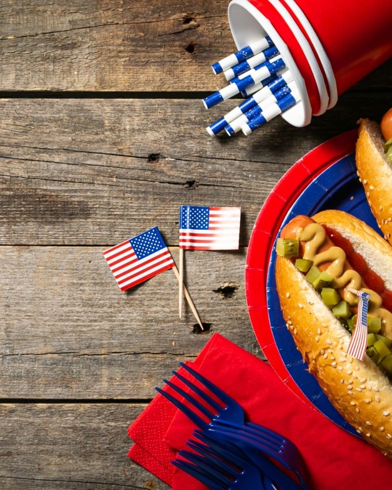 Hot dogs, flags, and red cups on a wooden block