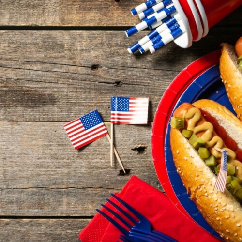 Hot dogs, flags, and red cups on a wooden block