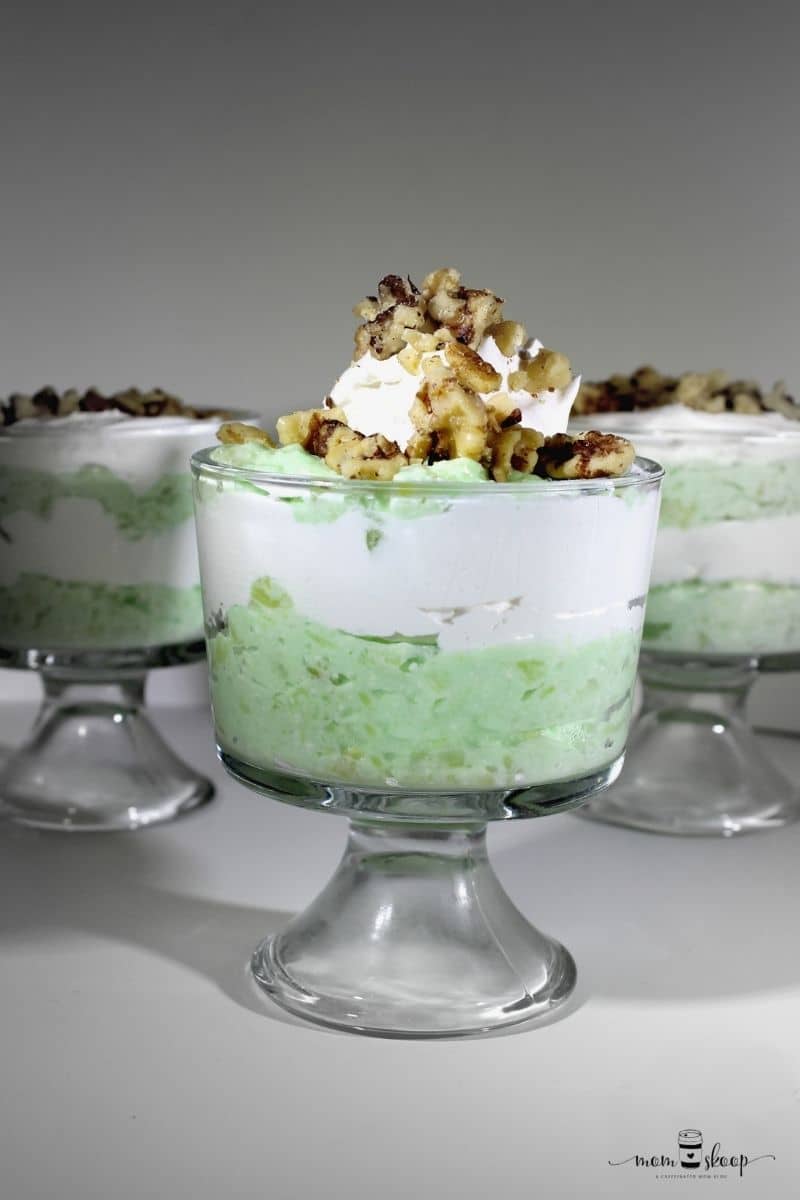 Glass dessert bowls with lime jello, topped with whipped cream and walnuts