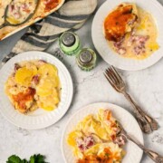 Plates with scalloped potatoes, cheese, and ham.