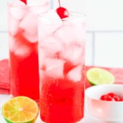 Lemon-lime soda, ice cubes, grenadine, and a maraschino cherry in a tall glass.