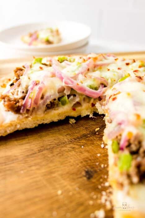 ground beef pizza on a wooden cutting board