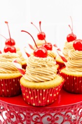 7 Root Beer float cupcakes with cherries and a straw sticking out of each cupcake.
