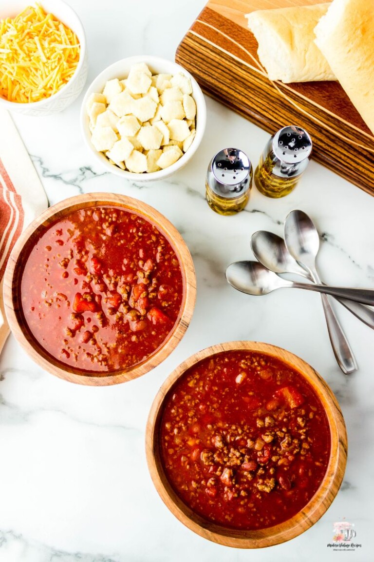 Two wooden bowls full of chili with ground beef, tomatoes, and kidney beans