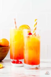2 collins glasses full of orange juice, vodka, ice, grenadine syrup, and cherries