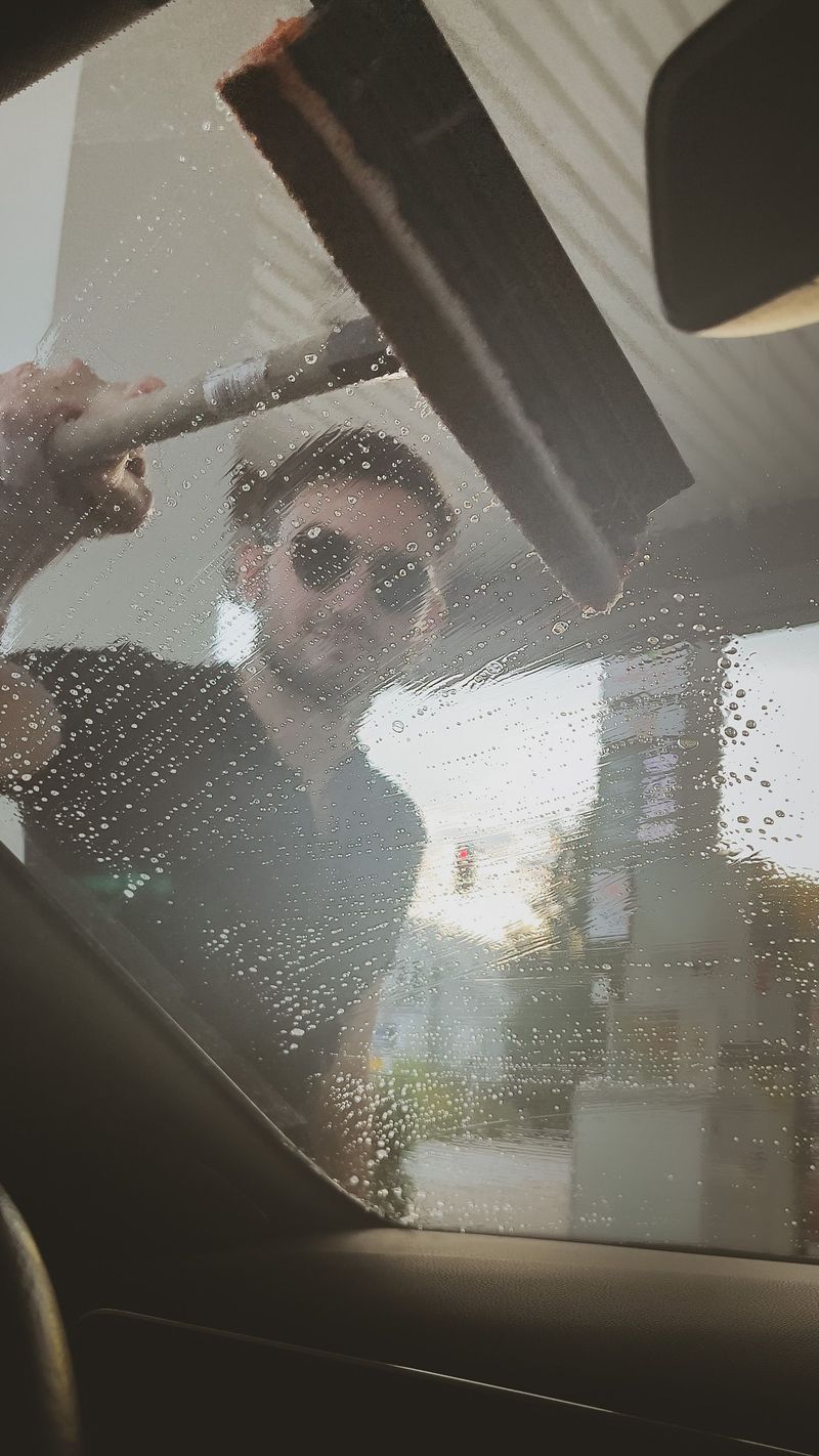 Cleaning the windshield by hand at a gas station
